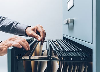 A man opening a file cabinet filled with files - Coren Law Group P.C.