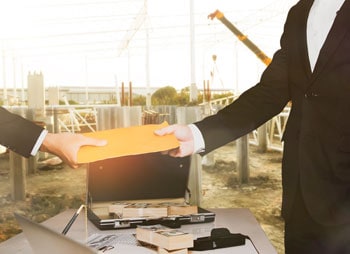Man in suit handing envelope to another man, with briefcase of cash nearby, symbolizing wage - Coren Law Group P.C.