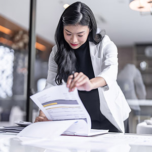 Woman reviewing documents in an office, illustrating Workplace Investigation Services. The background shows a gavel and scales of justice